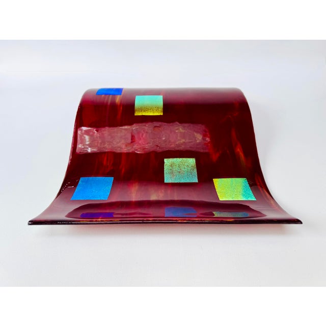 A bold postmodern wall sculpture in deep ruby-red fused glass. The rippling rectangular form is layered with iridescent...