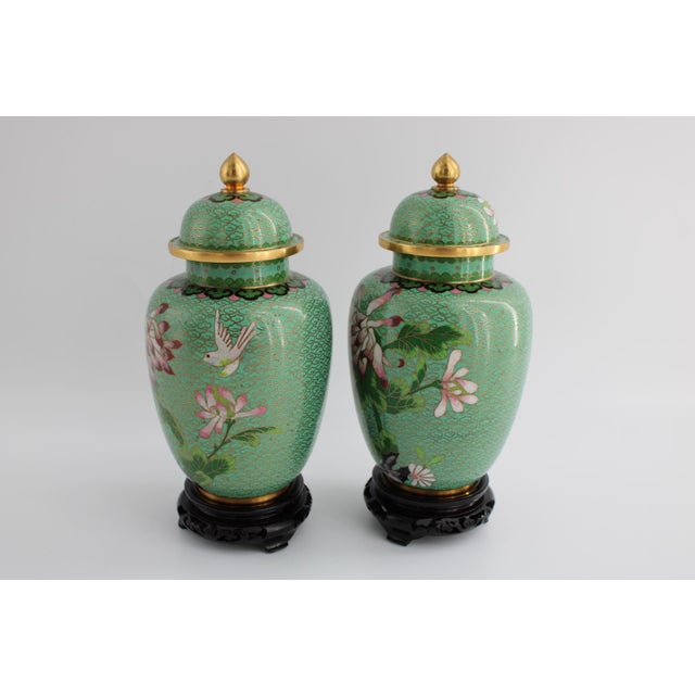 Vintage Pair of Chinese Cloisonne Urn Vases in Gorgeous Green with fine, detailed work. 8” Tall. The wooden stands are...