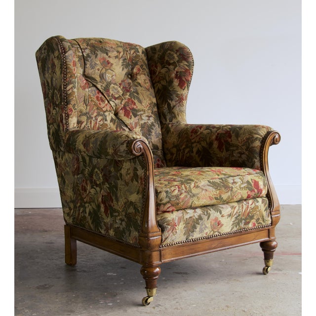 This English-style wingback has a button-tufted back, generous wings, and rolled arms that end in carved, exposed-wood...