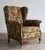 This English-style wingback has a button-tufted back, generous wings, and rolled arms that end in carved, exposed-wood...