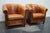 This pair of cognac-colored leather club chairs come from the Netherlands. They are upholstered with cognac-colored...