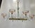 Six-light chandelier with a horizontal gold-plated metal frame, featuring clear glass arms that curve slightly upward and...