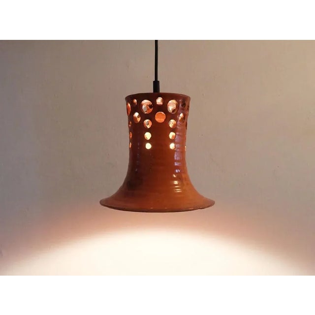 Very beautiful 1970s pendant light. The shade is made of orange glazed ceramic with some red and black. The hole structure...