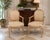 Elegant pair of vintage Louis XVI style armchairs featuring carved wood frames with a softly distressed, warm cream...