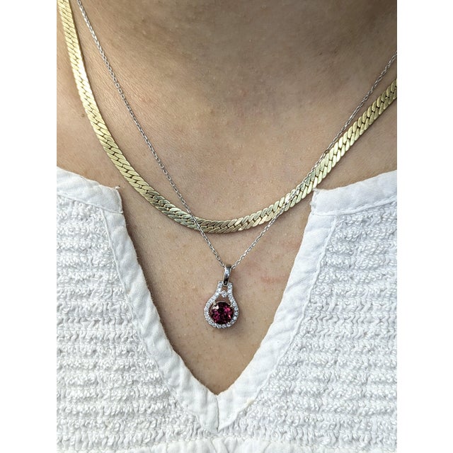 A celebration of color and craftsmanship, this round pendant features a 0.98 carat rubellite tourmaline encircled by a...