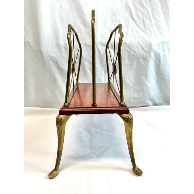 A beautiful mid-century Hollywood Regency brass magazine rack featuring graceful scalloped lines and an Art Nouveau...