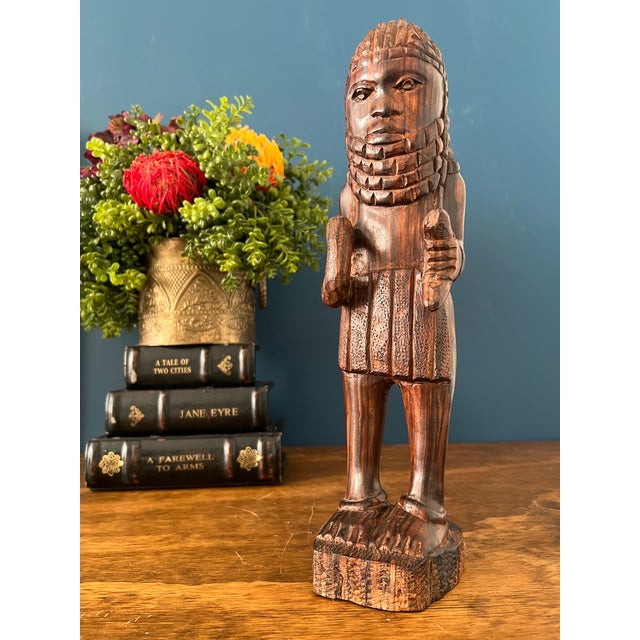 A striking hand-carved Kuba figure, executed in richly grained mahogany and elevated on an integrated base. The sculpture...