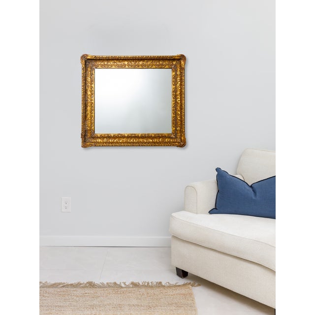A substantial antique mirror featuring a richly carved wood frame with original gilt finish. The ornamentation is bold but...