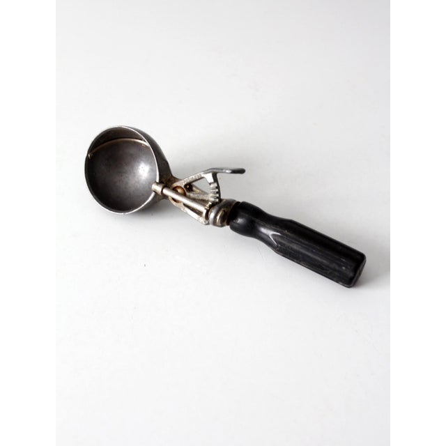 This mid-century Peerless ice cream scoop is a classic example of vintage kitchenware, featuring the original Peerless...