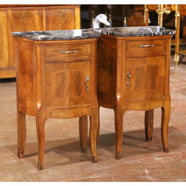 Crafted in France circa 1880, this elegant pair of antique Louis XV-style bedside tables features richly figured walnut...