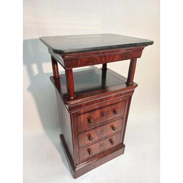 Sheath-shaped pedestal in mahogany from Cuba. The upper part rests on four columns, its top is in black marble. The lower...