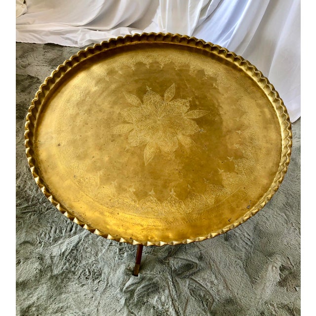 Beautifully hammered designed brass tray with ruffle edge and folding teak spider base with leg brass caps.