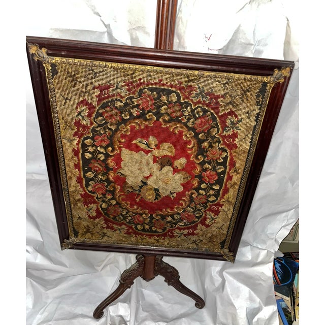 Victorian needlepoint fire screen in a walnut frame and tripod stand. Corner brass decorative pieces. Great colors and...