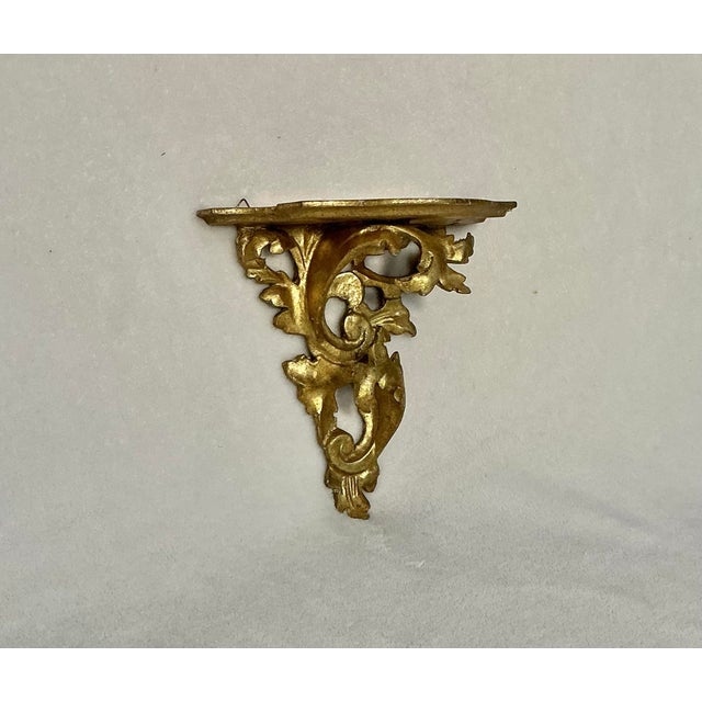 Vintage Italian giltwood wall bracket shelf, features hand-craved wood, rococo style foliate scrolls and a gold gilded...
