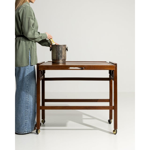 Here is a bar cart, its dark walnut, two-tier, castor wheels the first thing to catch the eye. The piece dates to Early...