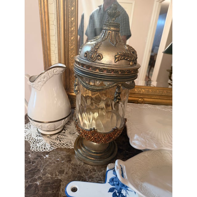 Impressive vintage Neoclassical-style decorative covered jar featuring a substantial clear glass body surrounded by...