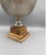 Elegant silver-tone metal pedestal bowl displayed on a substantial carved wood base. The combination of the cool-toned...