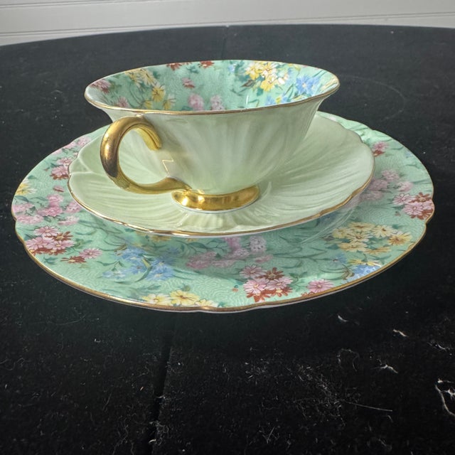 A stunning example of the coveted "Melody" chintz pattern. This trio includes a fluted teacup with an interior floral...