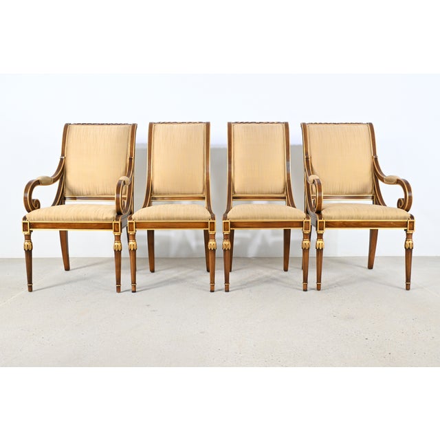 An elegant set of eight neoclassical-style dining chairs crafted in richly grained wood with refined gilt accents,...