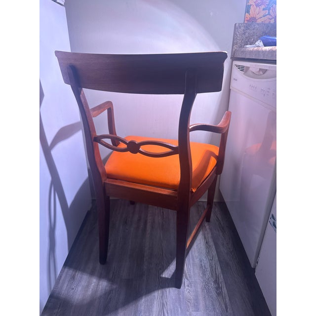 An exceptional Mid-Century Modern armchair featuring a striking architectural wood frame and rich burnt orange upholstery....