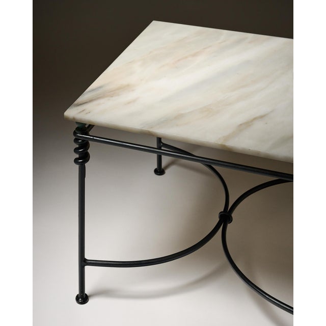 Coffee table from France with a square marble top in cream tones. The marble is supported by an iron base with an x-shaped...