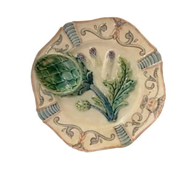 An antique French artichoke plate with a globe artichoke head sauce well and three asparagus spears. Surround by a...