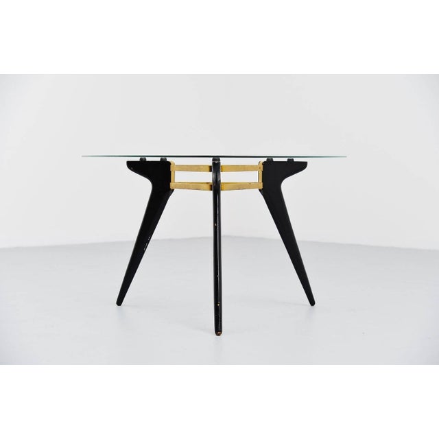Very nice Belgian coffee table with black lacquered wooden legs, brass connected frame and a triangular glass top. This...