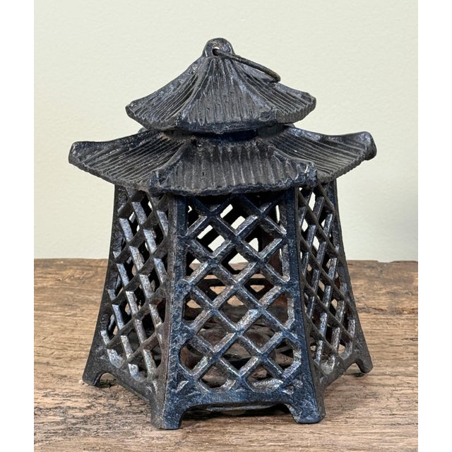 This cast iron hanging lantern is modeled in a Japanese pagoda style with tiered roof detailing and open lattice sides and...