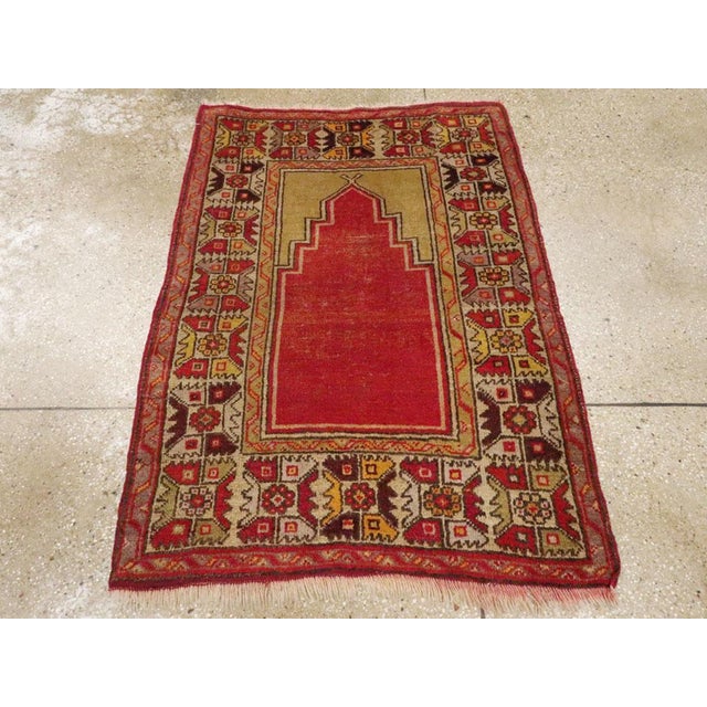 An antique Turkish Anatolian throw rug. The open red niche field is set under golden yellow plain spandrels and within an...
