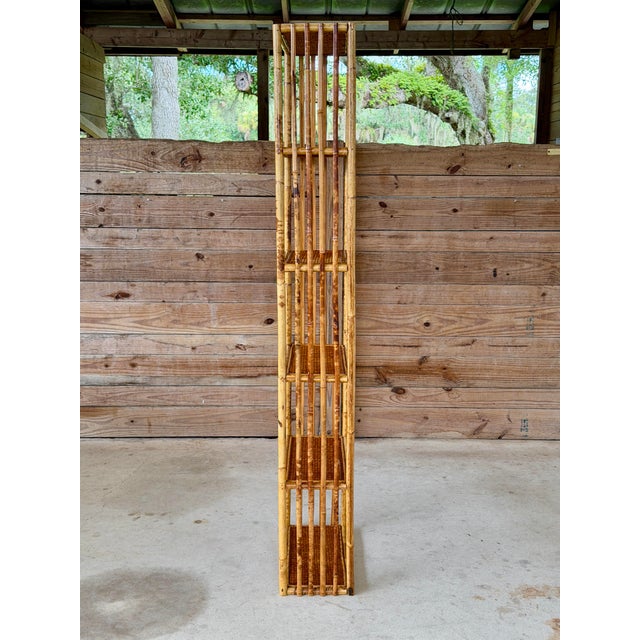 A wonderfully tall and narrow vintage rattan wall shelf or étagère featuring six woven rattan shelves and slender vertical...