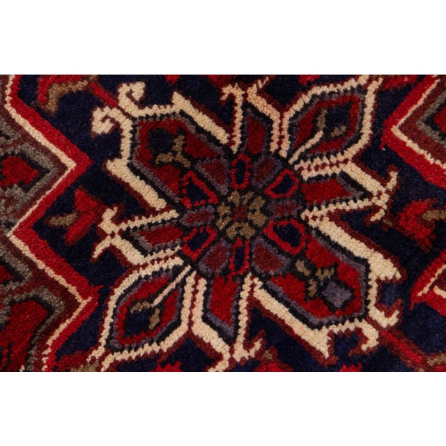 Beautiful vintage Persian Heriz hand-knotted wool rug with a red color field. This rug has a brown frame and multicolor...