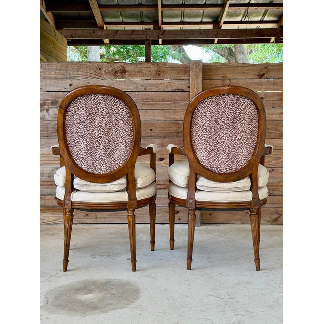 A handsome pair of antique Louis XVI style fauteuil armchairs featuring elegant oval backs, scrolling arms, carved rosette...