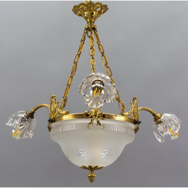 French neoclassical style gilt bronze and glass four-light chandelier. This beautiful chandelier features three arms each...