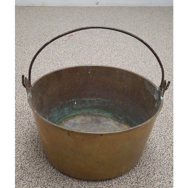An antique thick cast brass pot with a forged iron bail handle from th mid-19th-century. Almost a quarter inch thick cast...