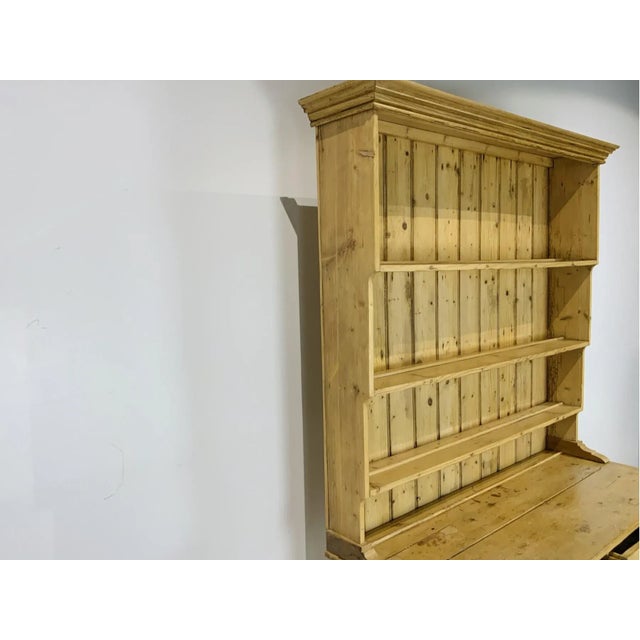 A well-proportioned, smaller two-part English country pine Welsh cupboard dresser with a molded cornice, three step-back...