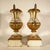 A pair of lacquered and gilded wooden palm holders with wrought and gilded iron handles, resting on a prominent square...