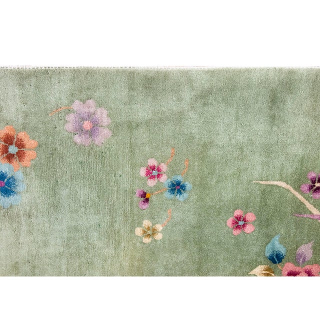 This hand-woven Chinese Art Deco wool rug from the 1940s features a vibrant array of floral motifs scattered across a...