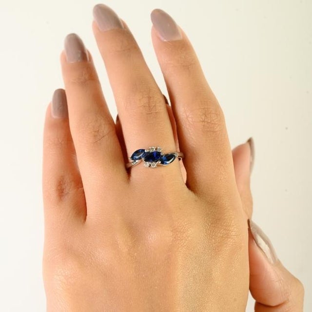 This vintage-inspired cluster ring showcases 3 marquise-cut blue sapphires totaling approximately 1.4 carats, beautifully...