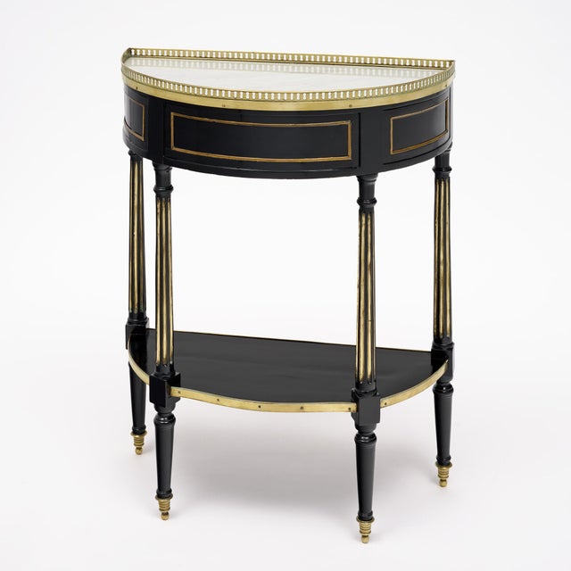 An exceptionally elegant French Louis XVI demi-lune console table, circa 1790, crafted in ebonized mahogany and retaining...