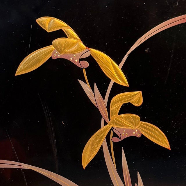 This vintage cabinet is finished in glossy black. The door is decorated with an elegant orchid motif (ran), with long,...