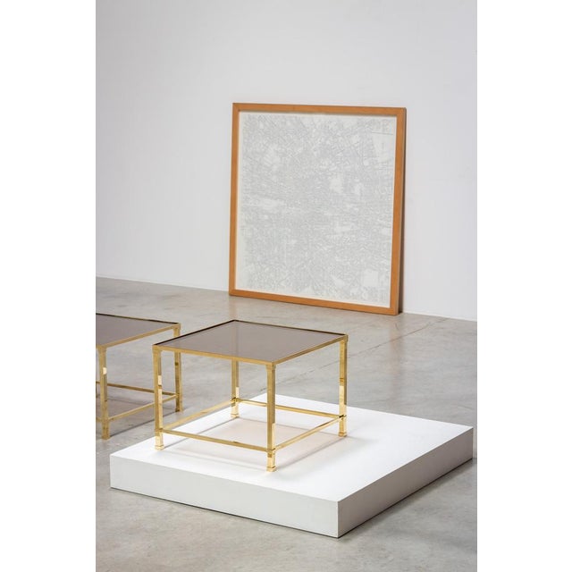 Sophisticated side tables designed in France, circa 1970. Brass structure supporting a smoked glass top. Classic...