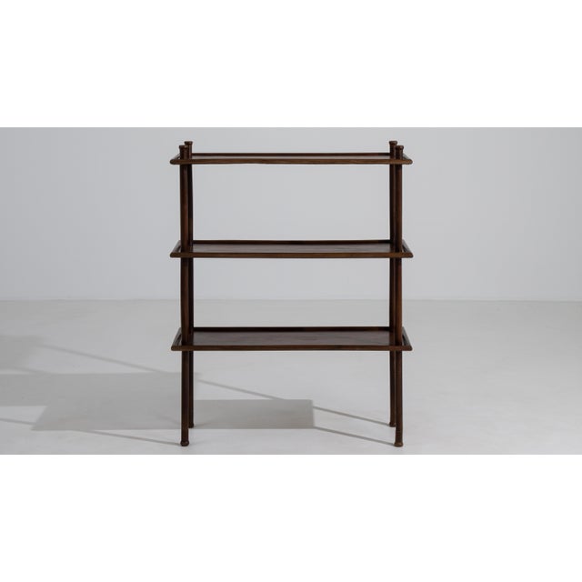 A mid-century modern etagere with open shelves and a slim vertical frame. The design allows for display without visual...
