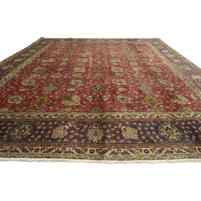 This hand-knotted wool vintage Persian Tabriz rug features an allover geometric floral pattern surrounded by a classic...