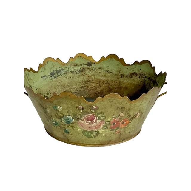 A charming vintage French tole planter featuring a softly distressed sage-green finish, delicate hand-painted floral...