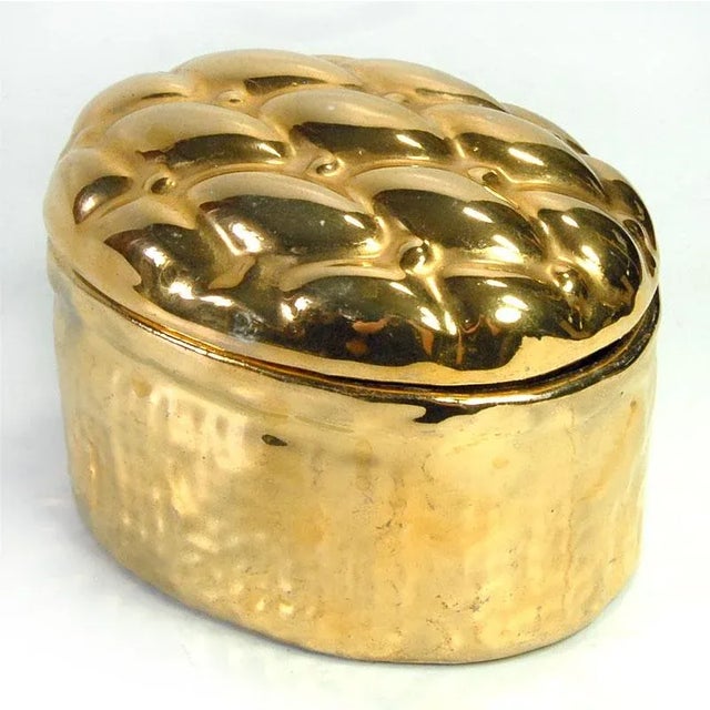 A highly decorative oval ceramic box with gold plating. Originally from the Netherlands, it measures 8 x 10 x 7.5 cm.