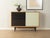 Classic chest of drawers from the 1950s. Walnut veneer body with two black and cream-white glass sliding doors, one shelf,...