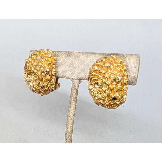 1960s goldtone 3d flower textured half hoop clip earrings. Marked "Hattie Carnegie" in script in a cartouche on the backs...