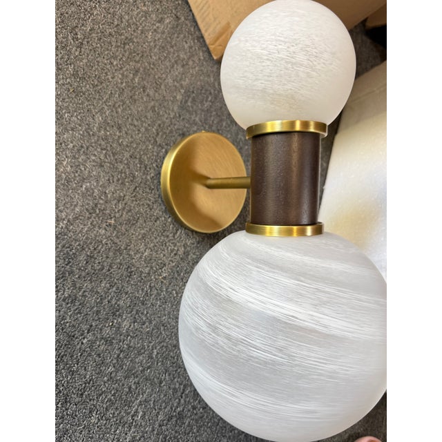 Dumbbell style sconce with offset globes of opal swirl glass with a gray-washed wood neck and antique brass mounting...