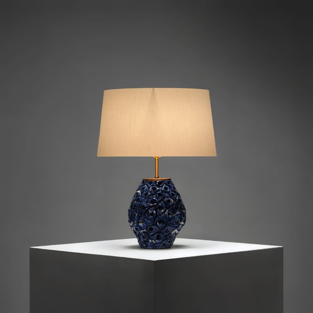 This Danish stoneware table lamp from the 1960s combines a deeply textured blue and white glazed base with a slender brass...
