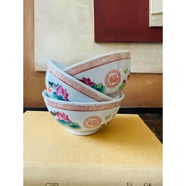 A colorful set of three vintage Chinese porcelain bowls featuring a lively fish and lotus flower design in vibrant...